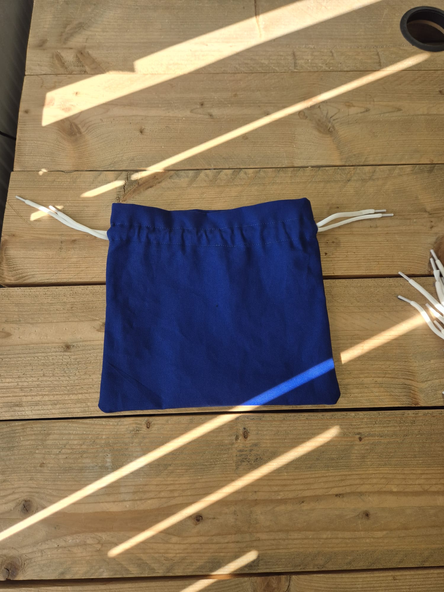 Blauw upcycled opbergzakje van reststof met witte trekkoorden, open weergegeven